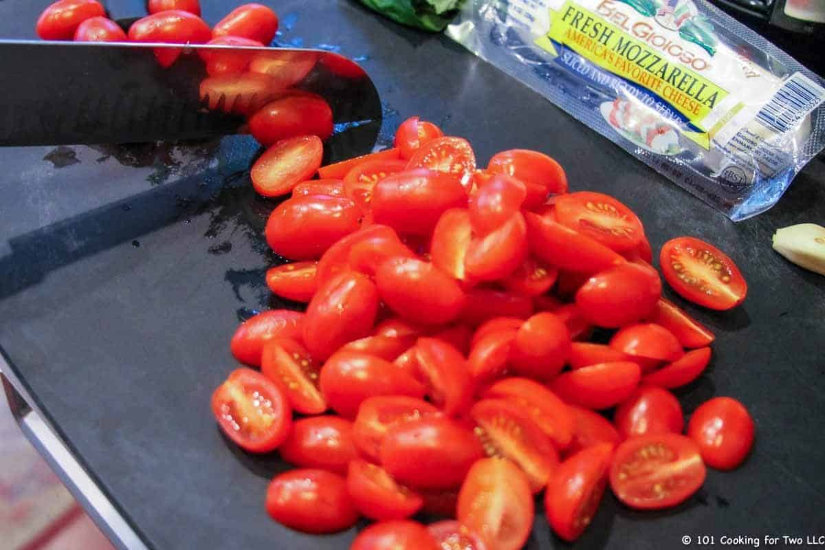 cherry tomatoes cut in half on black board.