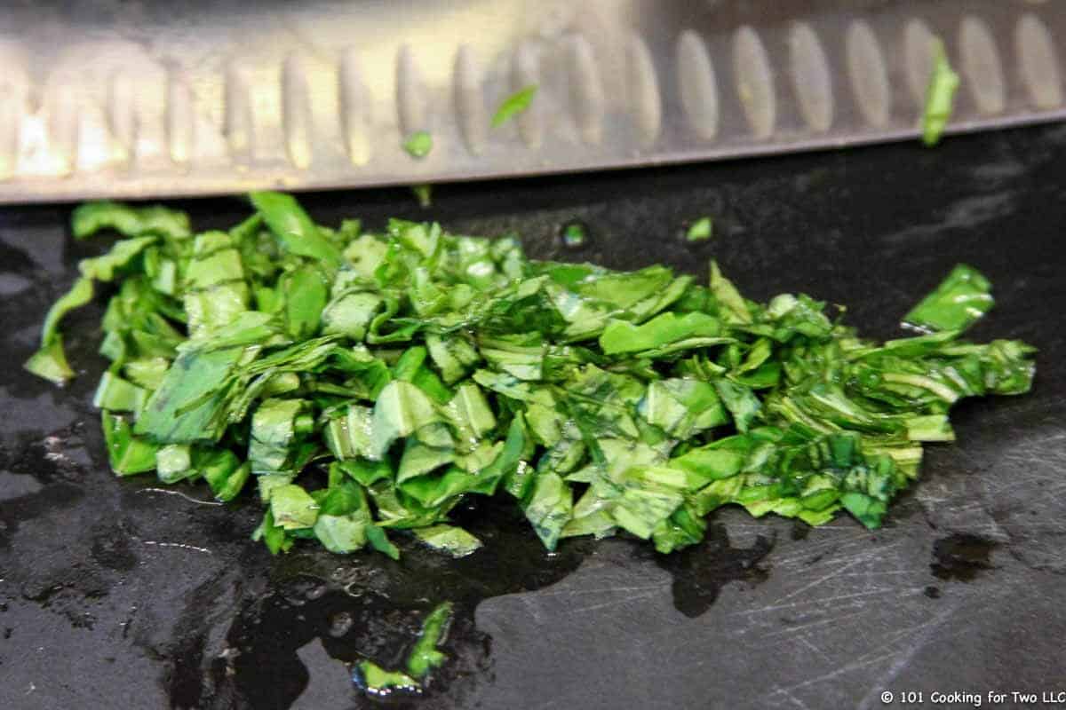 chopped fresh basil on black board.