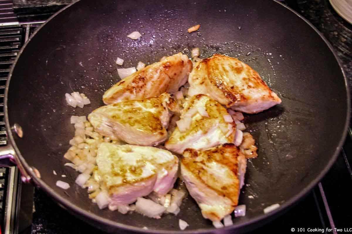 browned chicken with onion in black pan