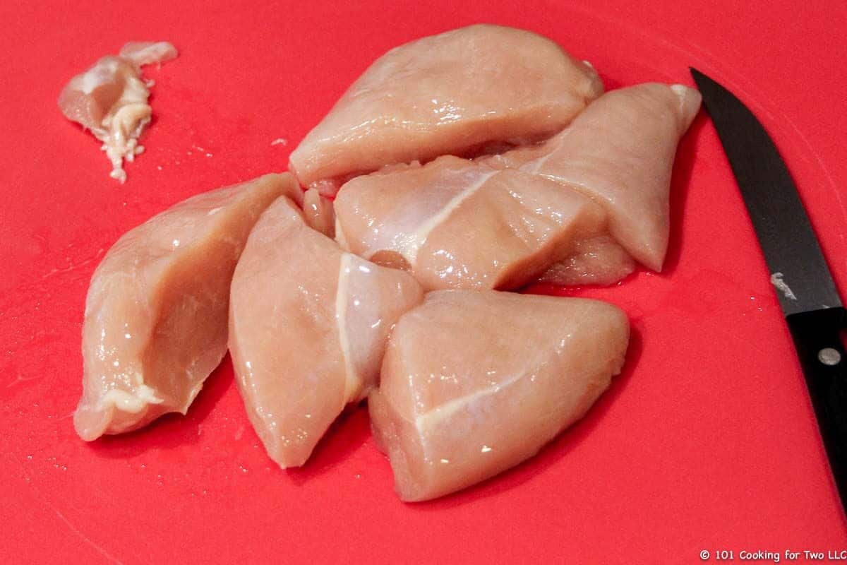 raw chicken trimmed on red board with knife