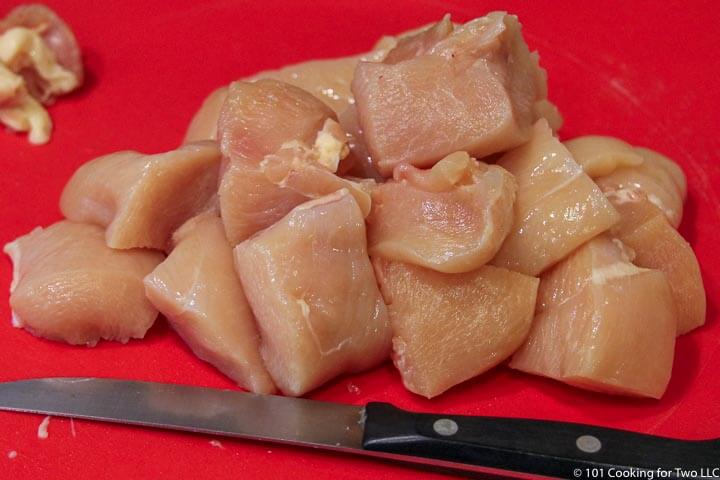 trimmed chicken on red board.