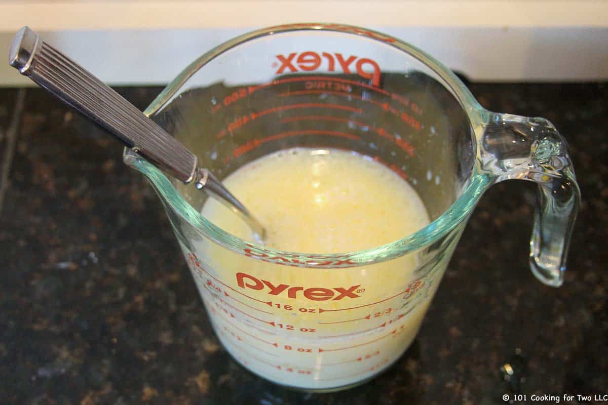 Mixing milk, oil and egg in cup.