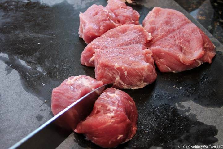 cutting pork tenderloin on black board.