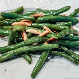 green beans with almonds on a white plate