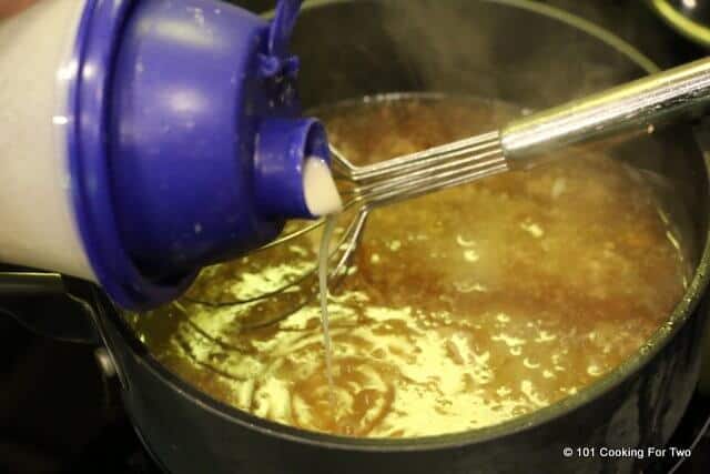 image of adding flour mixture to the boiling liquid in a black pan