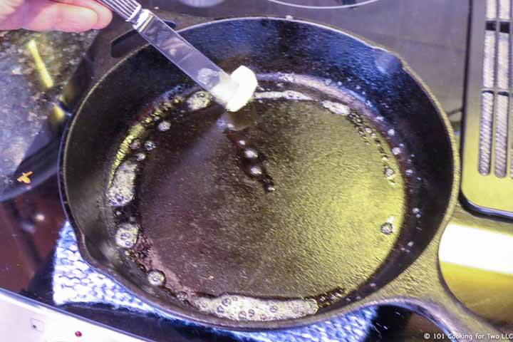 adding butter to a cast iron pan.