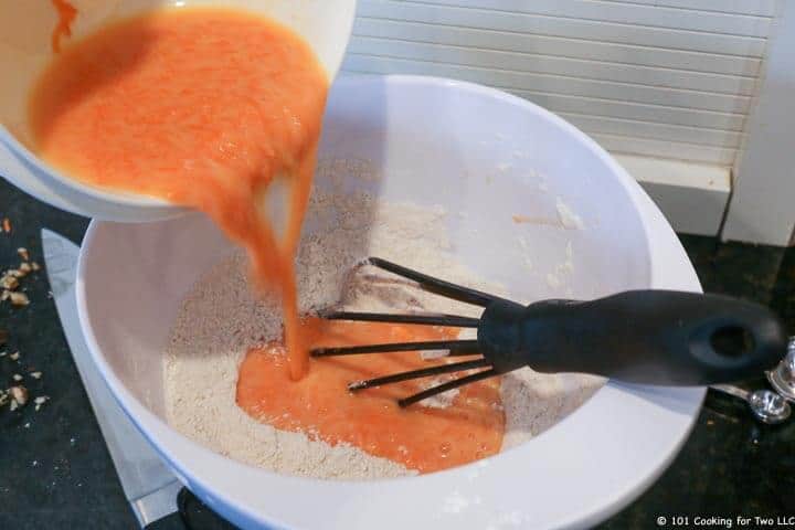 whisk in bowl mixing orange liquid into dry ingredients