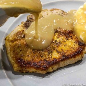 a fried pork chops with gravy on a gray plate