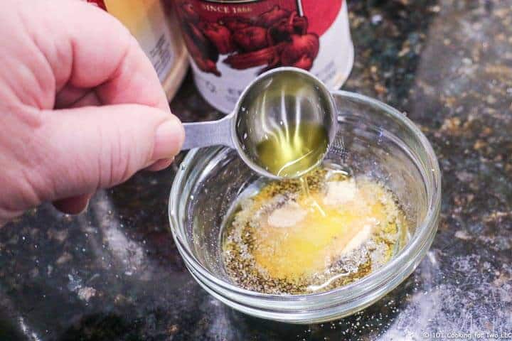 adding oil to cheese and spices in small bowl