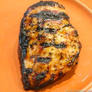 nicely cooked chicken breast with grill marks on an orange plate