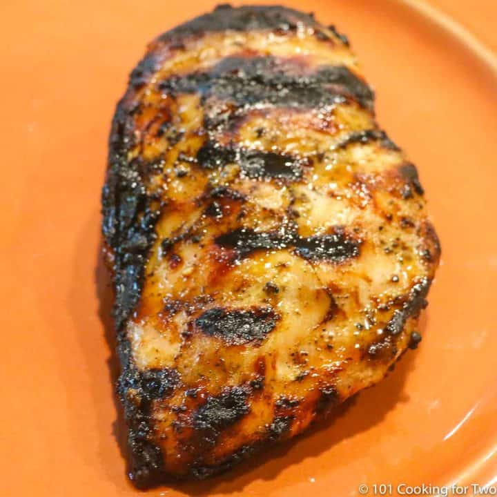 nicely cooked chicken breast with grill marks on an orange plate