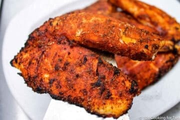 A pile of blackened tilapia on a white plate.