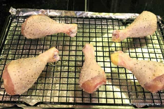 drumsticks on a rack on a cooking tray with foil ready for oven