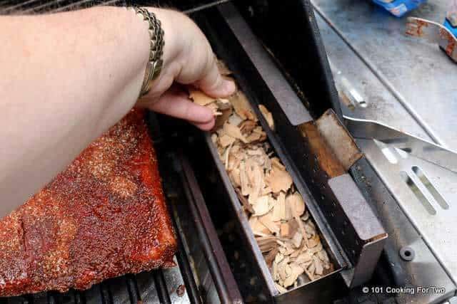 adding wood chips to smoker box.