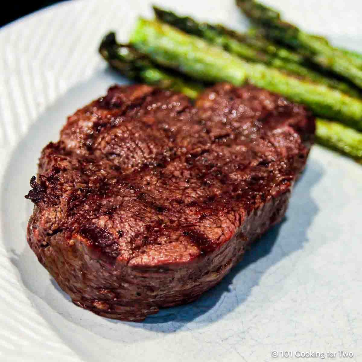 Grilled filet mignon on a white plate.