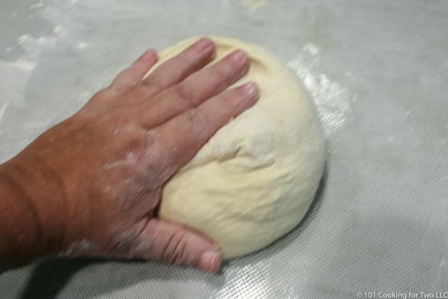 image of a ball of dough being kneaded on a white surface