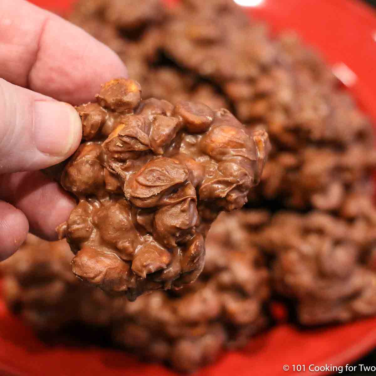 close up photo of a pile of Crock Pot Chocolate Peanut Clusters on a red plate