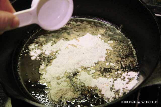 image of adding flour to fat in the black pan