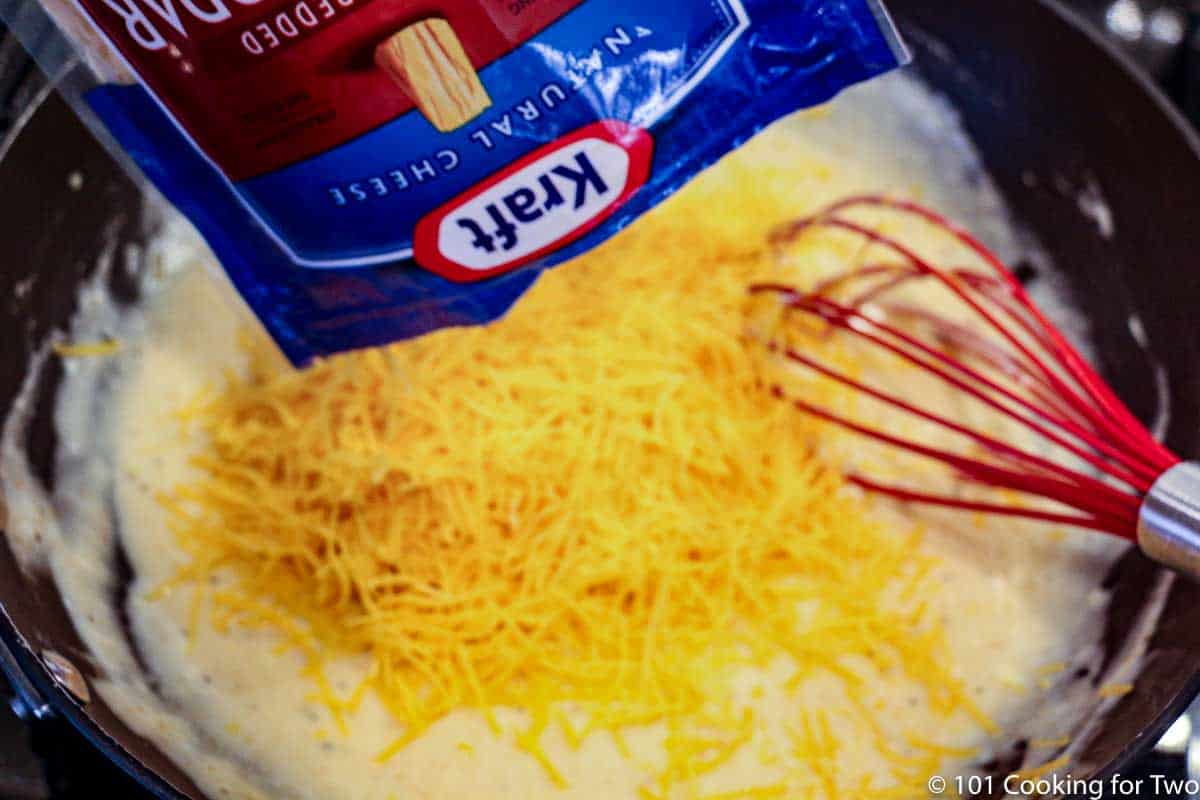 whisking cheese into sauce.