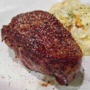 seared filet on a white plate with potatoes