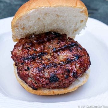 nicely done burger on a bun. All on a white plate