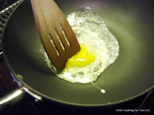 egg in black fry pan just starting to cook