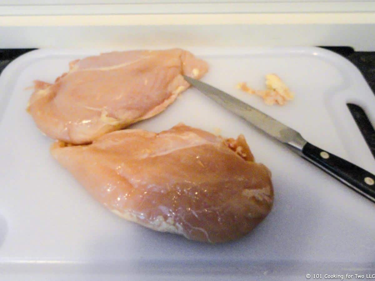 trimmed chicken breasts on a white board.