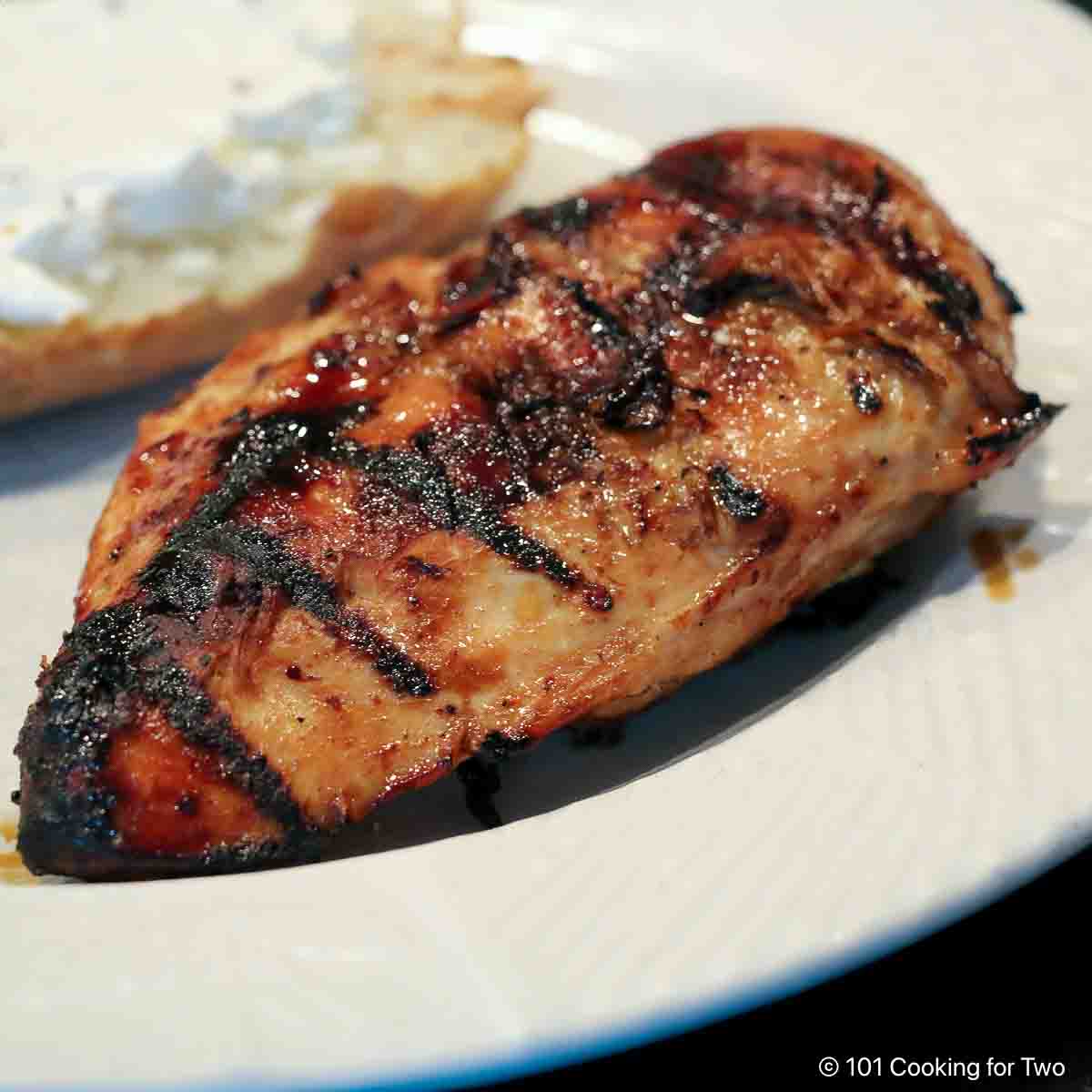 Honey glazed chicken breast on a white plate.