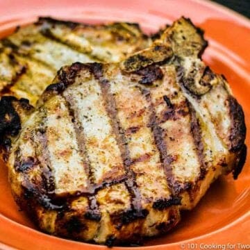 two grilled pork chops on an orange plate