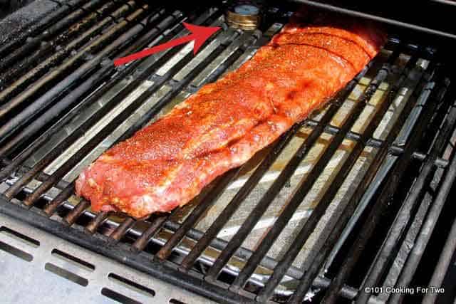 ribs on a grill with a surface thermometer.