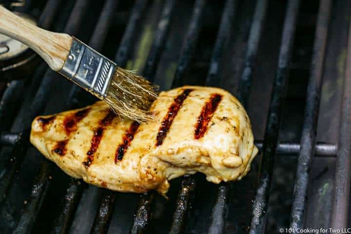 chicken on the grill being brushed with glaze