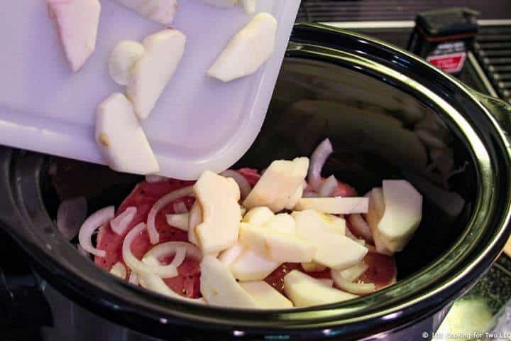 adding apple to the crock pot.