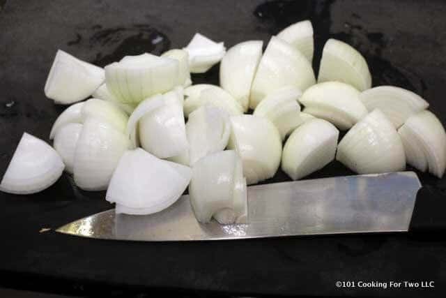 chopped onions on a black cutting board with a knife