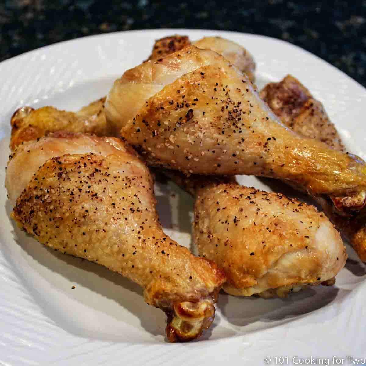A pile of chicken legs on a white plate.