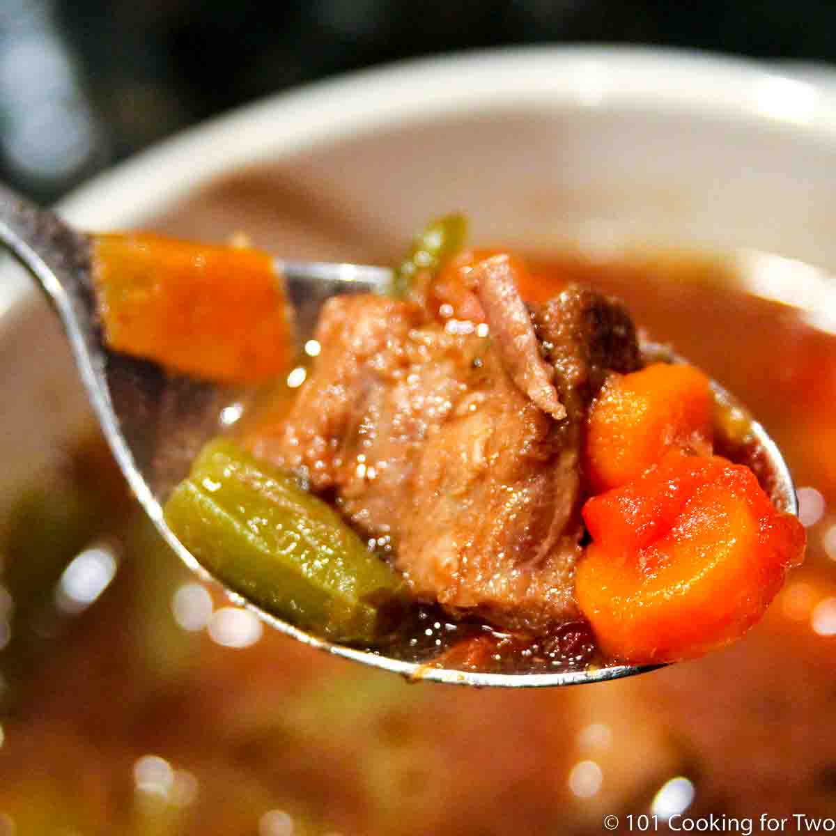 closeup image of vegetable beef soup in a large spoon.