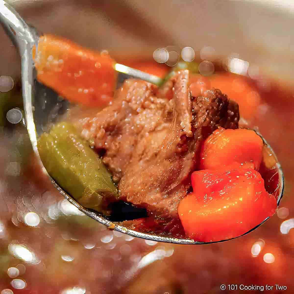 closeup image of vegetable beef soup in a large spoon.