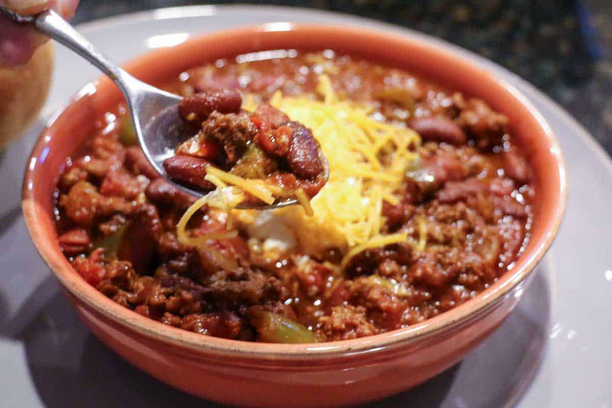 chili in bowl with spoon on gray plate