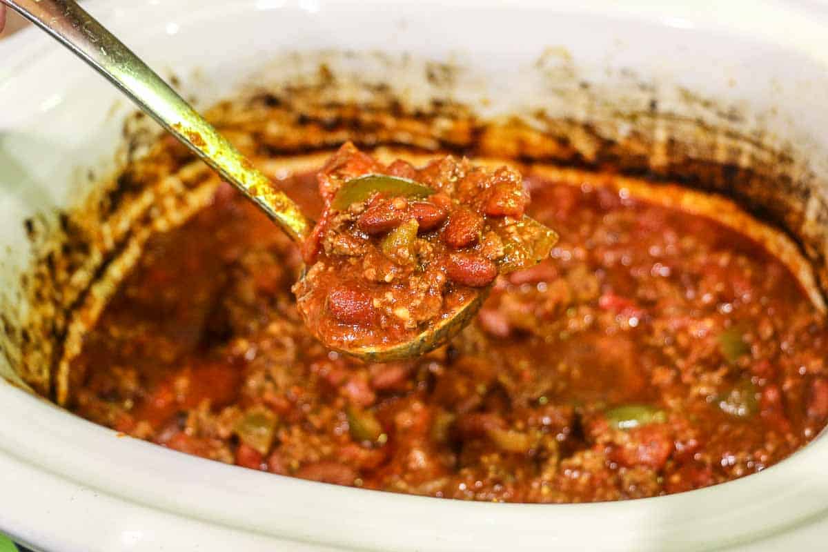 cooked chili in a ladel over the crock pot