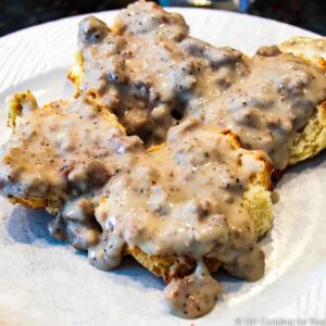 biscuit and sausage gravy on a white plate