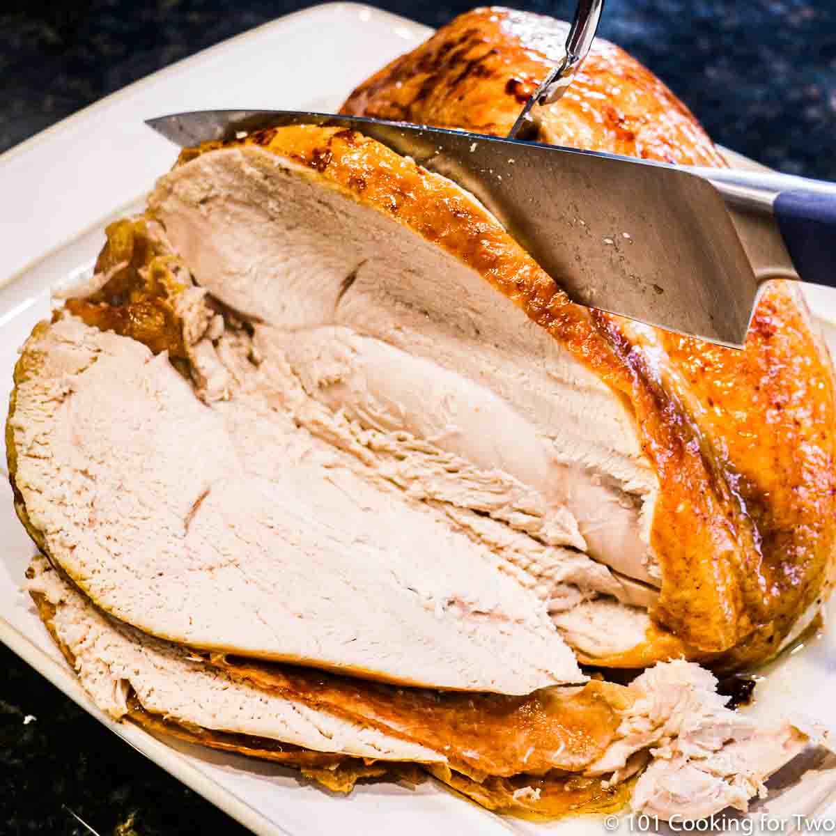 Slicing a turkey breast on a white platter
