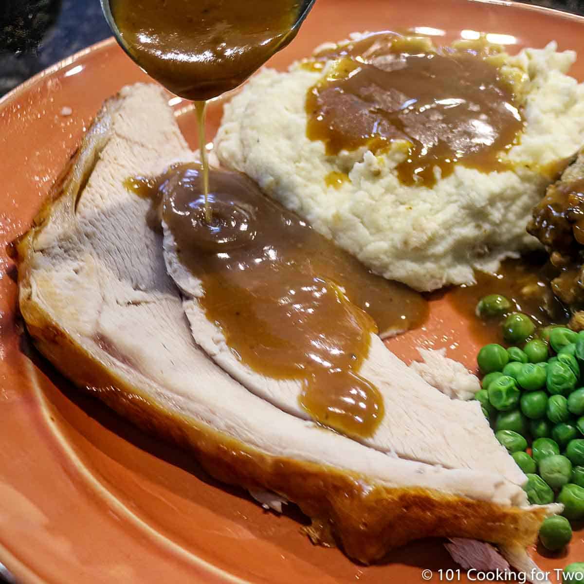 image of turkey slice on orange plate being covered with gravy