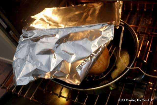 image of a cooking breast in an oven with a thermometer probe and tented with foil.
