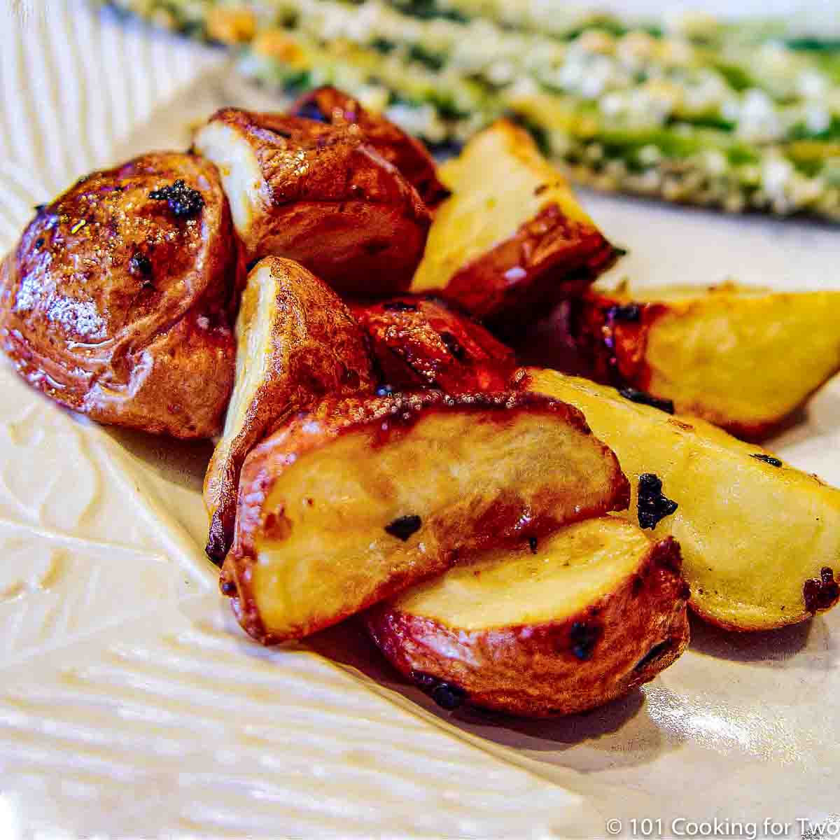 a pile of browned red potato quarters on a white plate.