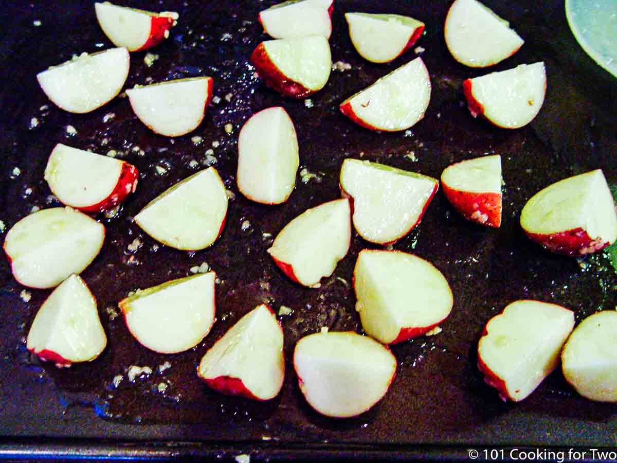 raw cut potatoes with seaonng on black tray