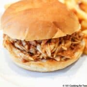 a shredded BBQ chicken sandwich on a white plate