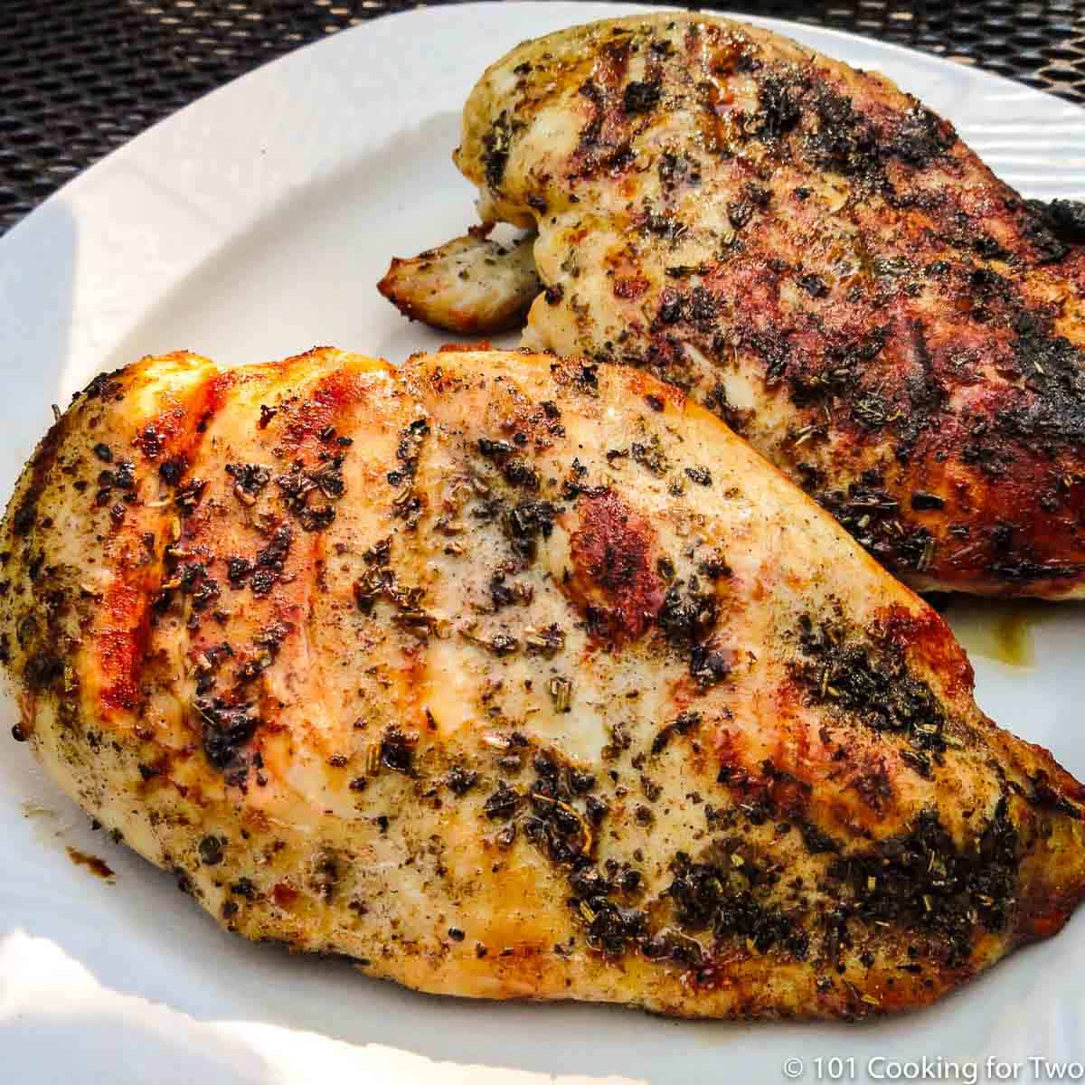 two Italian grilled chicken breast on a white plate