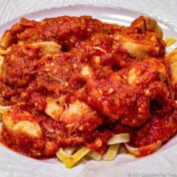 chicken marinara with pasta on white plate