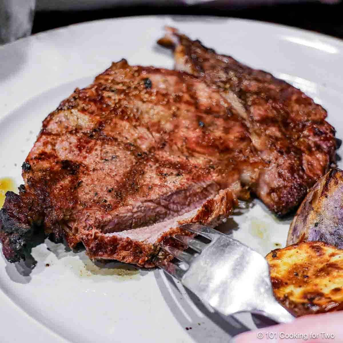 close up photo of a ribeye steak being cut. Medium Rare