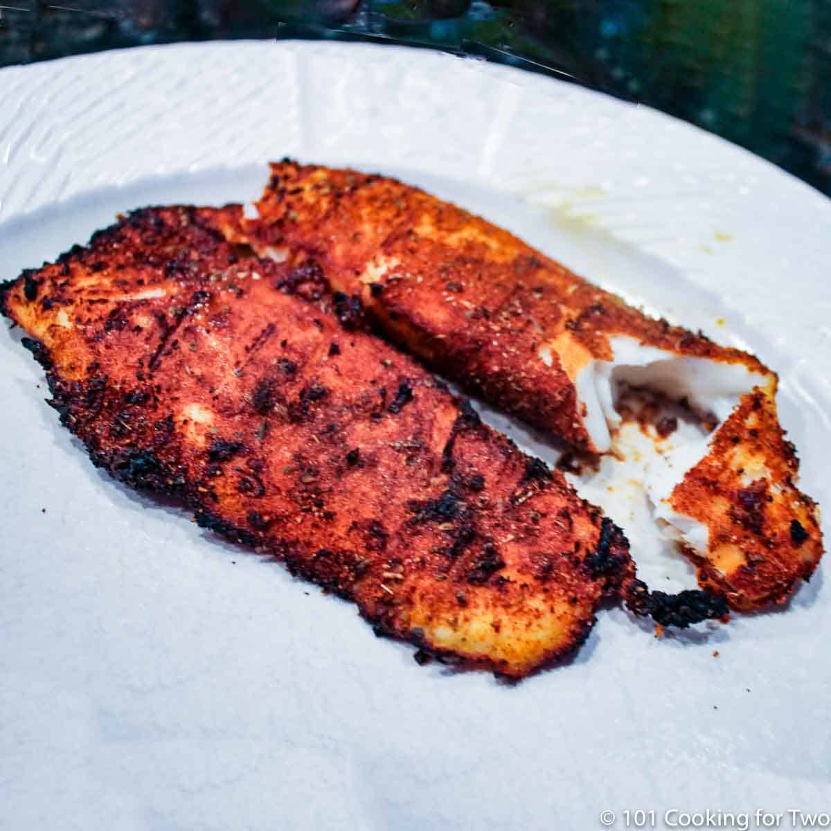 grilled tilapia flaking on a plate.
