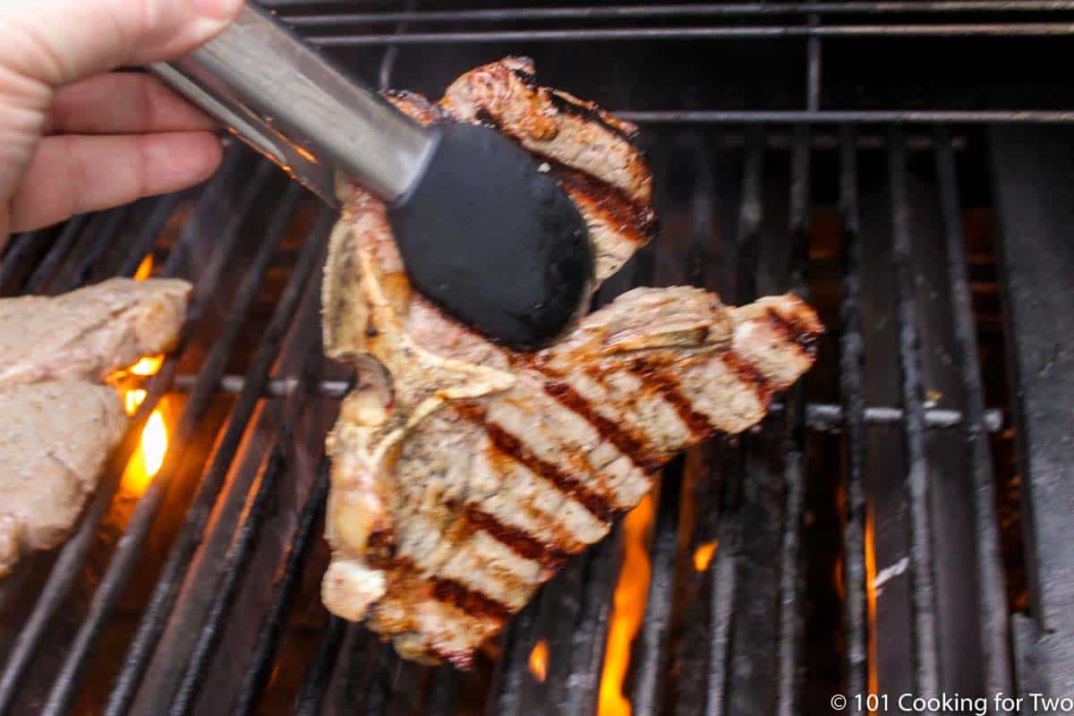 flipping steak on grill.